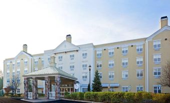 a hotel with a large sign above the entrance , surrounded by trees and a parking lot at Delta Hotels Basking Ridge