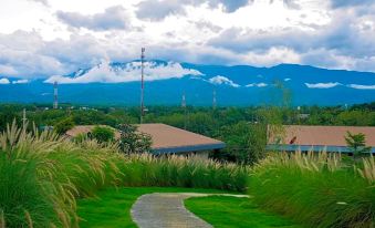 a serene landscape with mountains , trees , and clouds , as well as a path leading to houses in the foreground at The Sunnery Ville