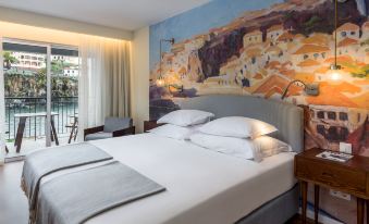 a large bed with white linens and a gray headboard is in a room with a mural on the wall at Pestana Churchill Bay