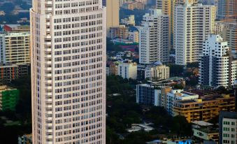 There is a large skyscraper in the center surrounded by other tall buildings, with one additional building on the side at Bangkok Marriott Hotel Sukhumvit