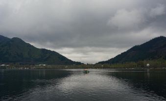 a dark lake with a mountain in the background and birds swimming in the water at Dawn