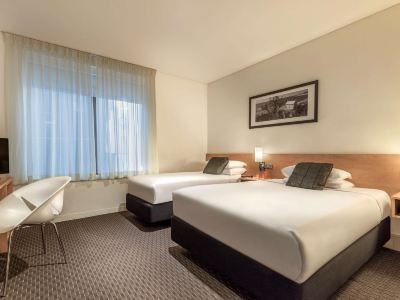 a hotel room with two beds , one on the left and one on the right side of the room at Ibis Melbourne Hotel and Apartments