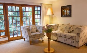 a living room with a couch and chair , a lamp , and a potted plant on a table at Summerhill Guest Estate