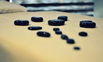 a group of black pebbles are arranged in a row on a yellow surface , with some smaller ones scattered around them at Hotel San Carlos Tequisquiapan