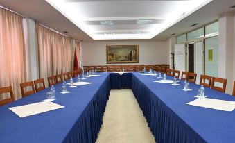 a long conference room with blue tablecloths , multiple chairs , and a whiteboard , set up for a meeting or presentation at Hotel Liss
