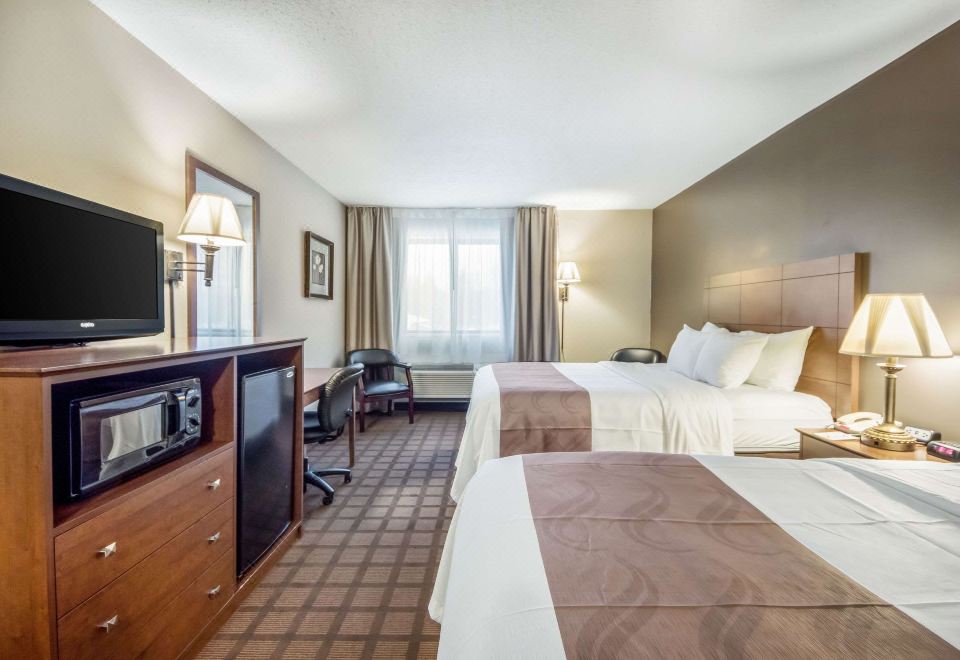 a hotel room with two beds , a desk , and a window , all neatly arranged in the room at Quality Inn & Suites Newberry