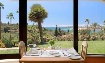 a dining room with a table set for a meal , surrounded by a beautiful view of the ocean at Hotel Casabela