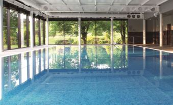 a large indoor swimming pool with a long lane and a long window looking out onto a green landscape at Macdonald Inchyra Hotel and Spa