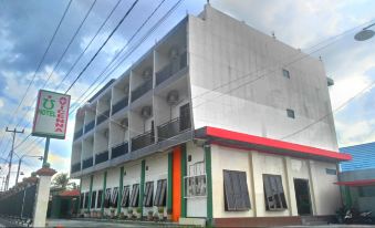 a large white building with a red and green awning , located in a city setting at Avicenna Hotel