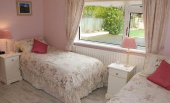 a pink bedroom with two twin beds and a window , providing a view of the outdoors at Lettermore