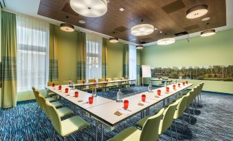 a conference room set up for a meeting with multiple tables and chairs arranged in a semicircle at Hey Lou Hotel Frankfurt Airport