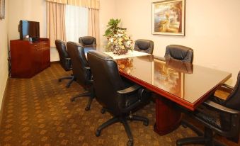 a conference room with a wooden table surrounded by black chairs , and a potted plant on the table at Franklin Inn and Suites