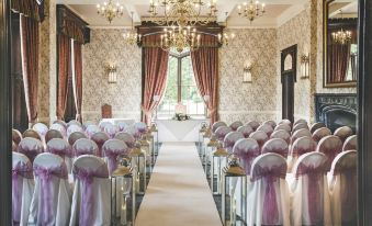 a large , elegant wedding ceremony room with rows of white chairs and a long aisle leading to a well - decorated venue at Rowton Castle