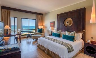 a luxurious hotel room with a large bed , white linens , and a view of the ocean at Sea Cliff Hotel