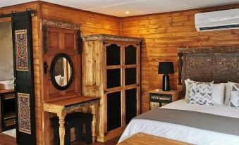a bedroom with wooden walls , a large bed , and a closet , along with other furniture such as a mirror and nightstand at River Rock Lodge