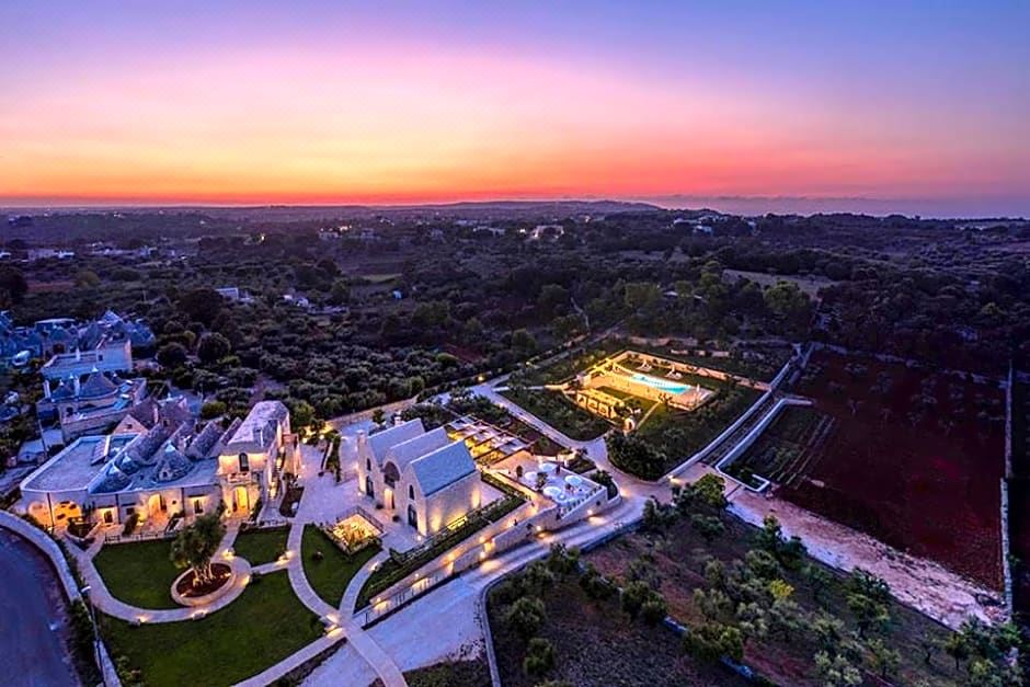 an aerial view of a large white building surrounded by greenery , with a sunset in the background at Ottolire Resort