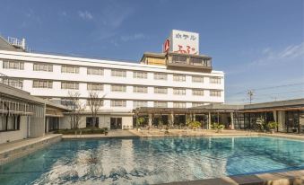 a large swimming pool is situated in front of a hotel with chinese characters on its sign at Hotel Fuji