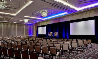 a large conference room with rows of chairs arranged in front of a stage , and two screens on the stage at Renaissance Dallas at Plano Legacy West Hotel