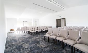 a large room with rows of white chairs arranged in a semicircle , likely for a meeting or event at Hotel Avenue - Avenue Hotels