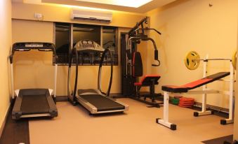 a well - equipped home gym with various exercise equipment , including a treadmill , weights , and a bike at Hotel Majestic Shillong