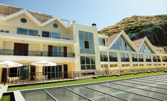 a modern building with large windows and balconies , surrounded by a grassy area and a patio at Eira do Serrado - Hotel & Spa