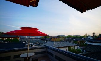 The outside patio area features a balcony with chairs and a table, providing a view of the city at Jeonju Dwaejikkum Pension