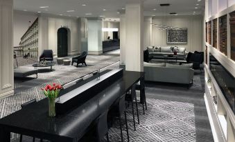 a modern office space with a black and white checkered floor , a reception area , and several chairs arranged around the tables at Hotel Manoir Victoria