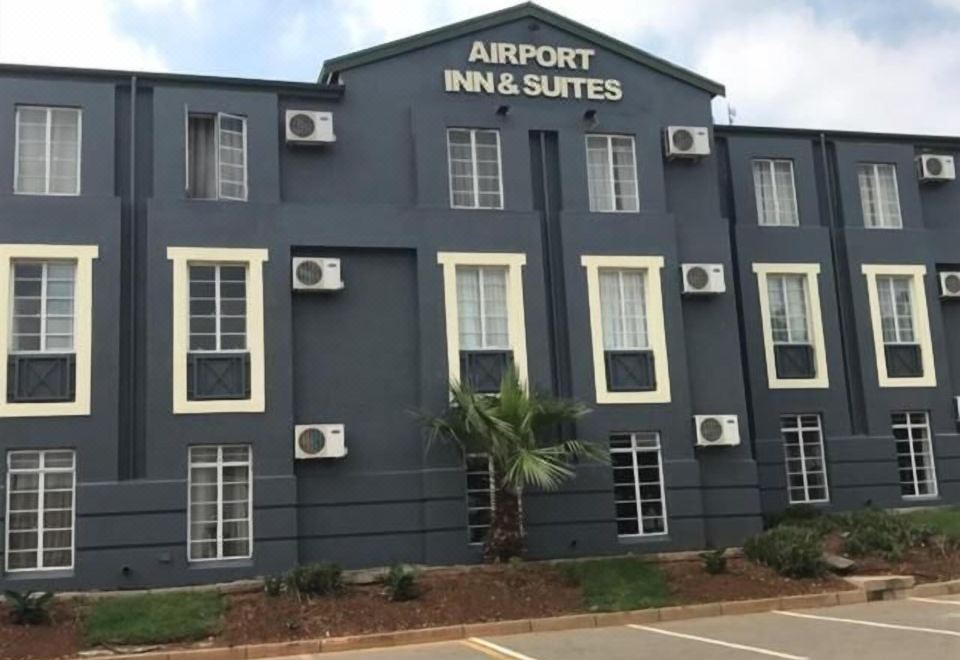 "a large , dark blue building with white trim and the words "" airport inn & suites "" written in gold" at Airport Inn and Suites