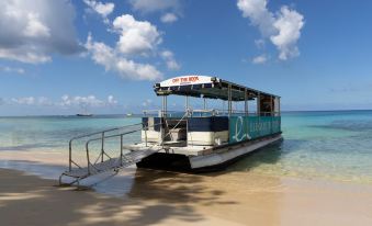 a boat with a blue roof is docked at the beach , with a clear blue sky and water surrounding it at Colony Club by Elegant Hotels
