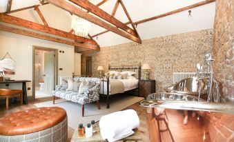 a cozy bedroom with a large bed , a bathtub in the corner , and a stone wall at Beadnell Towers Hotel