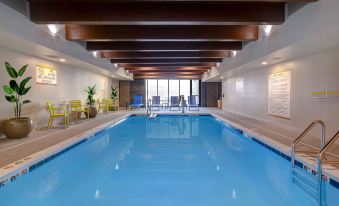 a large indoor swimming pool with a wooden ceiling and chairs in front of the pool at Home2 Suites by Hilton Dekalb