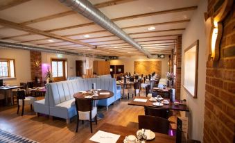 a modern restaurant with wooden floors , exposed beams , and blue booths , featuring multiple dining areas with tables and chairs at Tewinbury