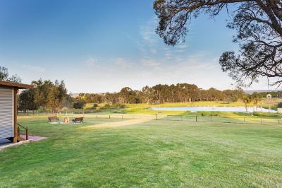 a grassy field with a lake in the background , surrounded by trees and a fence at The Swan Valley Retreat