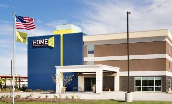 a large hotel building with a blue and yellow color scheme , located in a city setting at Home2 Suites by Hilton Baton Rouge