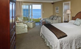 a luxurious hotel room with a large bed , couch , and balcony offering ocean views , decorated in white and brown colors at Stage Neck Inn