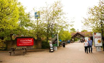 "a street scene with a bench and trees , a sign that says "" roadchef "" on the side" at Days Inn by Wyndham Sevenoaks Clacket Lane
