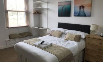 a white bedroom with a double bed , a desk , and a painting on the wall at Stanley Arms Hotel