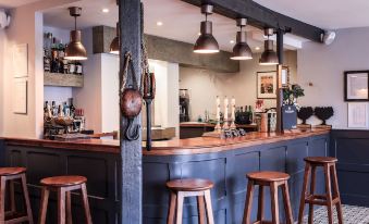 a modern , stylish bar with wooden stools and pendant lights , creating a warm and inviting atmosphere at The Ship Inn