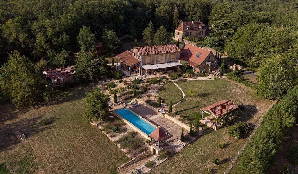 aerial view of a large house surrounded by trees and a swimming pool , located in a rural area at Le Lion d'Or en Perigord