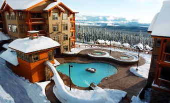 a snow - covered resort with a large pool surrounded by multiple buildings and a mountainous landscape in the background at Sundance Resort