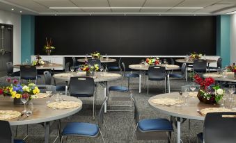 a conference room with round tables and chairs arranged for a meeting , with a black chalkboard in the background at Aloft Seattle Redmond