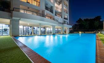a large swimming pool is illuminated by lights at night , with a building in the background at Goldsborough Place Apartments