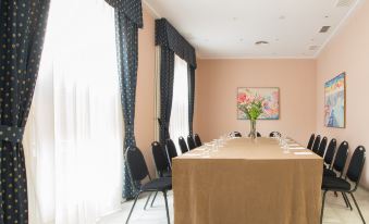 a long dining table with a brown cloth and multiple chairs is set up in a room with blue curtains at Hotel Inglaterra