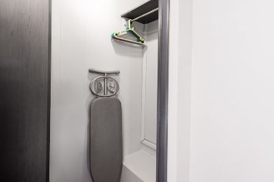 a white closet with a gray ironing board and an ironing board hanging from the ceiling at Village Hotel Liverpool