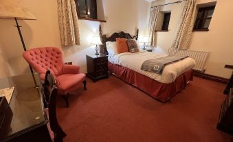 a cozy bedroom with a large bed , a desk , and a chair , surrounded by curtains and a rug at The Stanley Arms