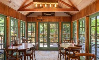 a wooden interior with green windows , wooden tables and chairs , and ceiling lights , giving it an open and airy feel at Weasku Inn