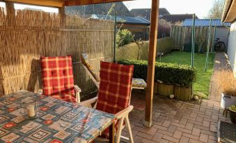 a patio with two chairs and a dining table set up for outdoor dining , surrounded by a lush green garden at Christine