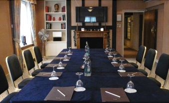 a dining room with a long table set for a formal dinner , featuring multiple place settings and wine glasses at Manor Hotel