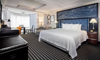 a large , well - appointed hotel room with a king - sized bed , a desk , a chair , and a television at Courtyard by Marriott Boston Brookline