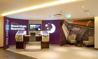 a hotel lobby with a check - in desk and a staircase leading to the second floor at Premier Inn Trowbridge